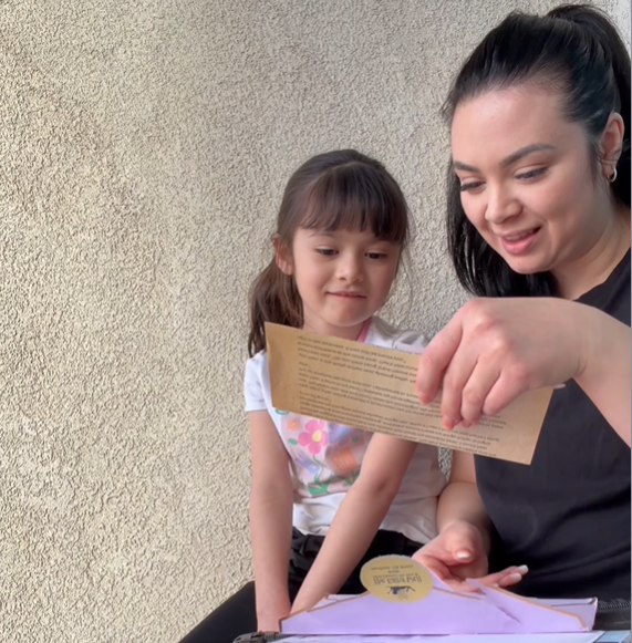 Woman and child looking at a letter together against a beige wall.